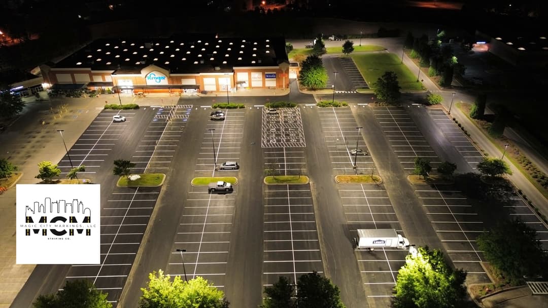 Aerial view of a lit empty parking lot at night near a retail store.