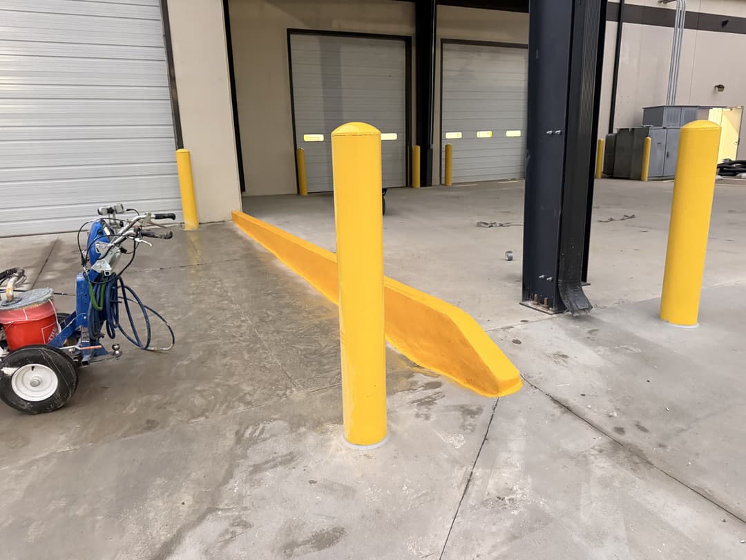 Yellow safety barriers and loading dock ramp in industrial warehouse setting.
