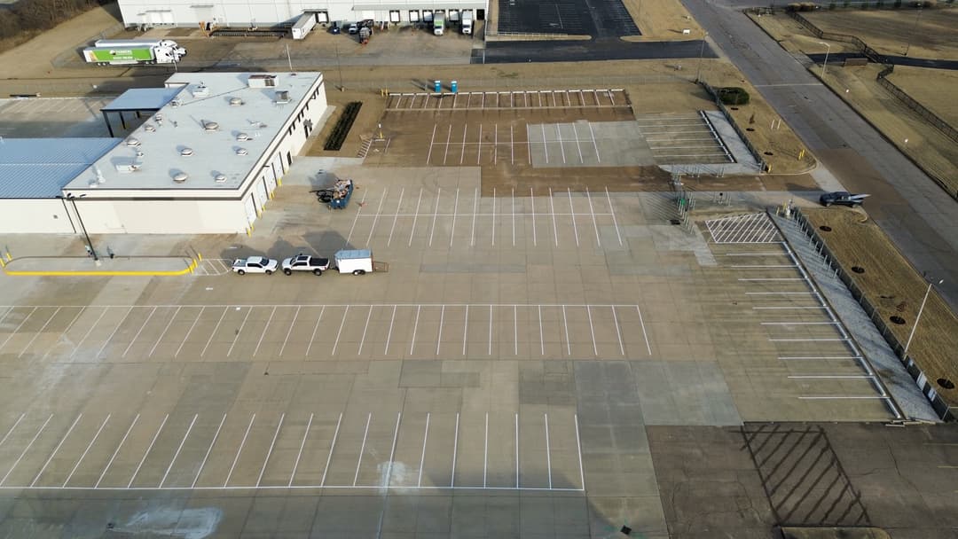 Aerial view of a large empty parking lot next to a commercial building.