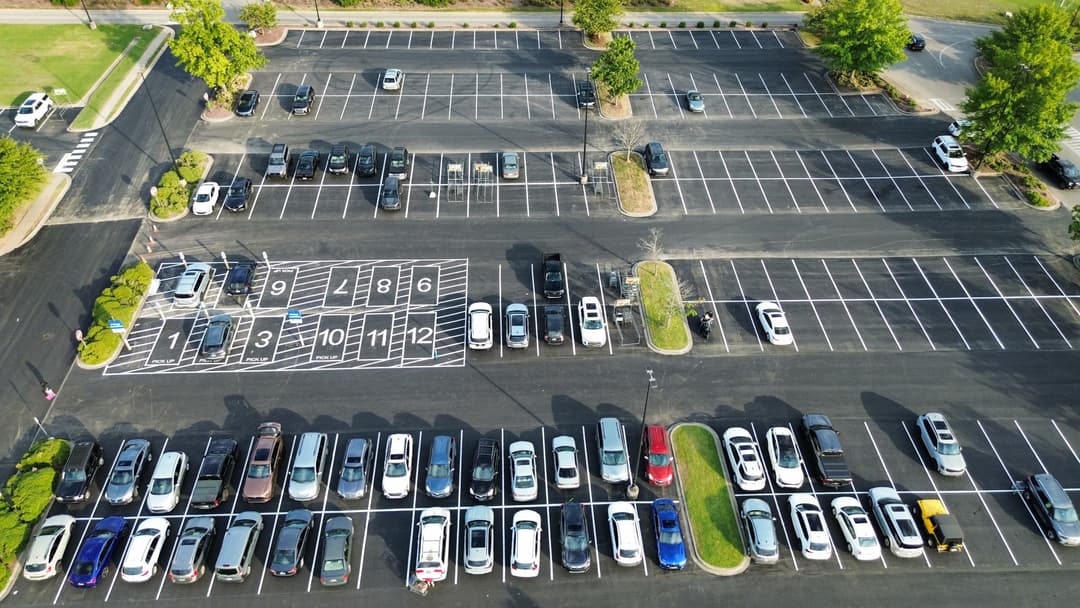 Aerial view of a nearly empty parking lot with organized parking spaces and few cars.
