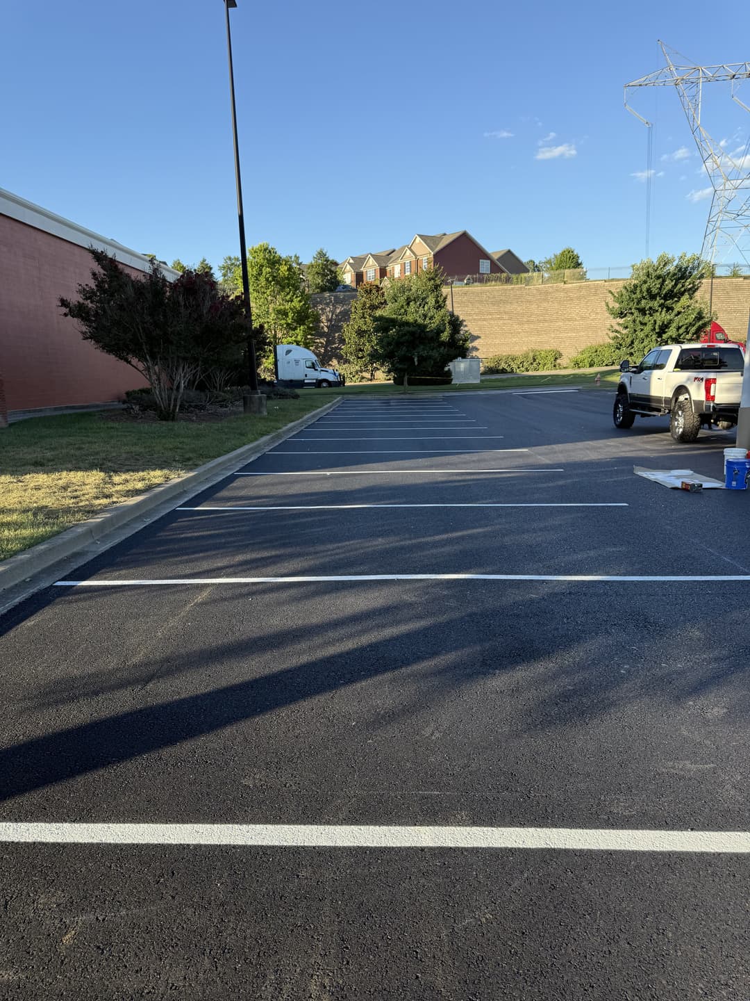 Empty parking lot with freshly painted lines and buildings in the background. Bright blue sky.